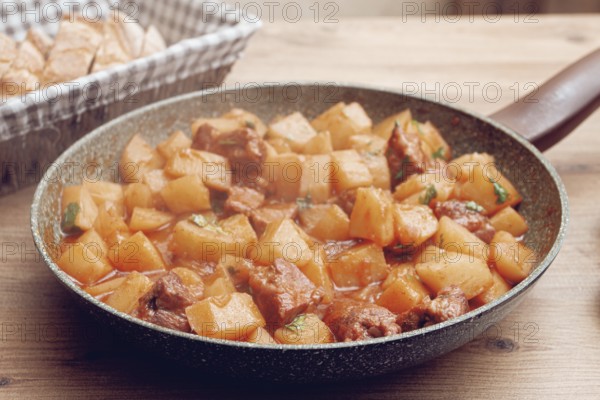 Hearty vegetable stew with meat, in a frying pan, with freshly baked bread, close-up