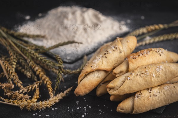 Fresh salted sticks with caraway seeds and salt in front of a pile of flour and cereals