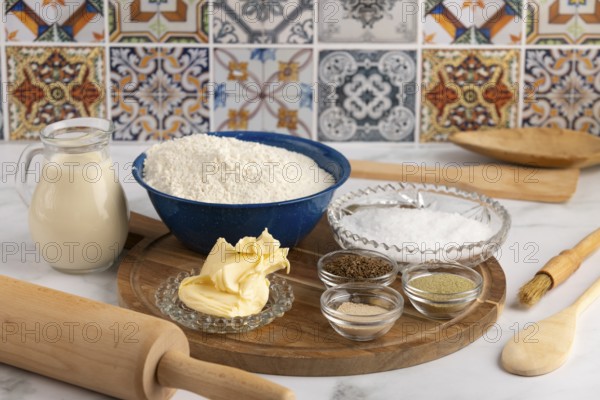 Baking ingredients, flour, butter, spices on wooden board in kitchen, with decorative tiles in background