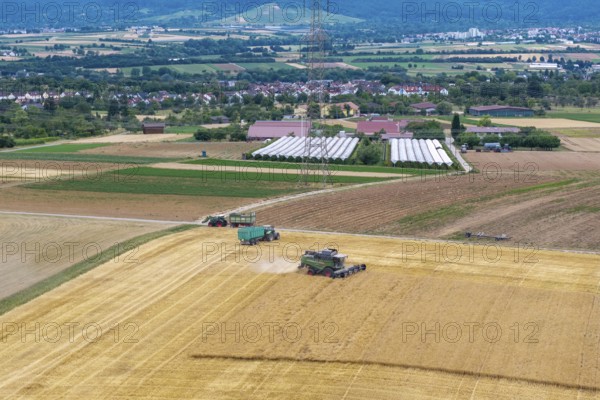 Extensive agricultural landscape with combine harvesters and tractors and fields against a mountain backdrop, Korb im Rems Valley, Baden-Württemberg, Germany