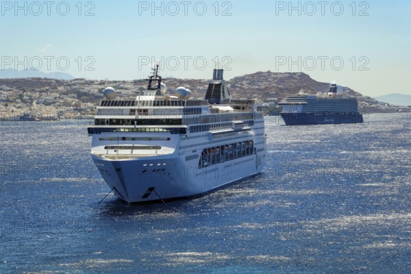 Mykonos, Cyclades, Greece - Cruise ships MEIN SCHIFF 5 and MSC LIRICA are located in the bay off Mykonos City. Old town with windmills. Cruise ships bring tourists to shore