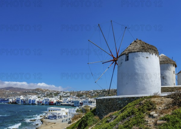 Mykonos, Cyclades, Greece - The six sixteenth-century windmills, lined up on a hill above Mykonos Town, Mykonos Chora, are the island's landmark. At the back, right by the sea, are the colorful houses of Little Venice. Mykonos is part of the Cyclades archipelago in the Aegean Sea