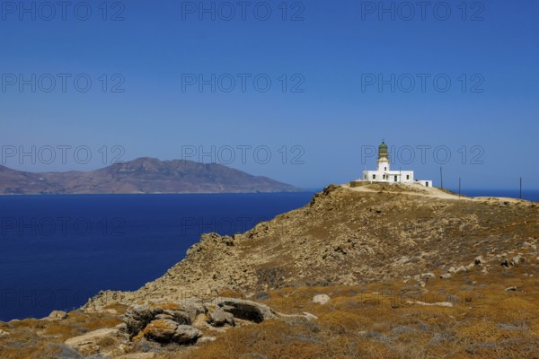Mykonos, Cyclades, Greece - The Armenistis lighthouse in the north of the island is a landmark and a popular destination for tourists. In the back is the island of Tinos