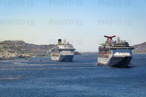 Mykonos, Cyclades, Greece - cruise ships CARNIVAL MIRACLE and COSTA FORTUNA are located in the bay off Mykonos City. Old town with windmills. Cruise ships bring tourists to shore