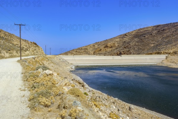 Mykonos, Cyclades, Greece - Dry Fokos Reservoir near Ano Mera. The Mykonos Municipal Water Supply and Sewage Management Company has two dams, Marathi Reservoir and Fokos Reservoir, to supply water to the island. Due to the prolonged drought, both are almost empty and are not being used