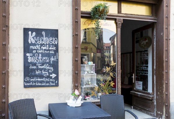 Funny advertising sign for eating cake in the old town of Naumburg (Saale), Saxony-Anhalt, Germany