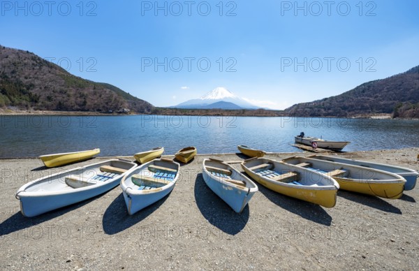 Rowing boats on shore, view across the lake to Mt Fuji volcano, Motosu Lake, Yamanashi Prefecture, Japan