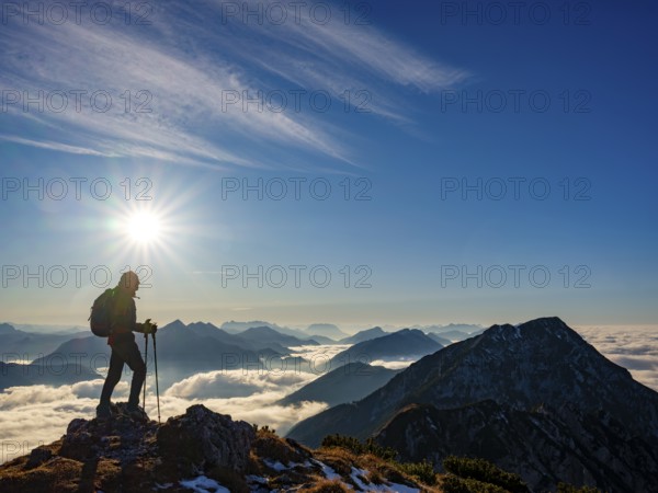 Mountaineer looking at blue-colored silhouette of mountains, fog in the valley, Hochstaufen, Chiemgau Alps, Upper Bavaria, Bavaria, Germany