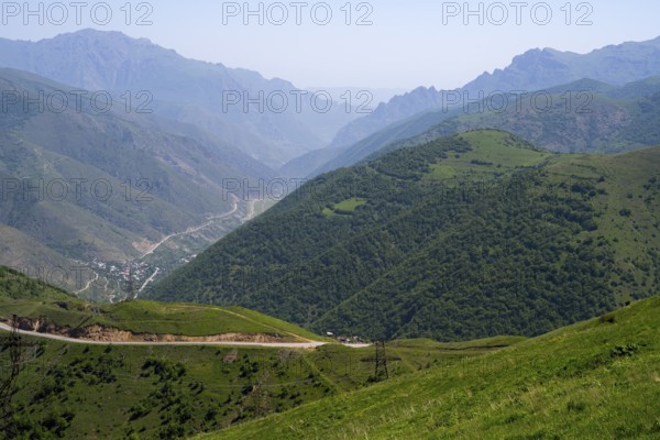 Panoramic view of a valley with road and green hills between mountains, view of Lernadzor surrounded by the mountains of the Zangesur Range, Sangesur, Syunik province, Caucasus, Armenia