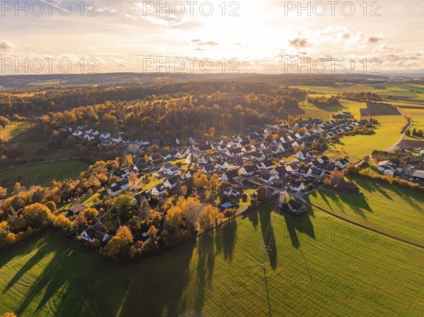 Wide view of a village in autumn atmosphere, surrounded by fields and wooded hills in sunlight, Lehenweiler, Aidlingen, Böblingen district, Germany
