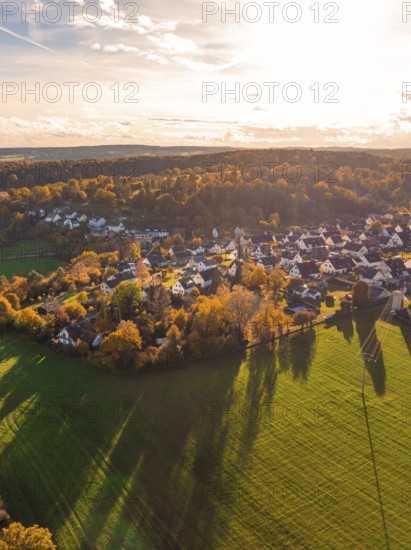 Sun-drenched village with houses and fields in the evening mood, wooded hills in the background, Lehenweiler, Aidlingen, Böblingen district, Germany