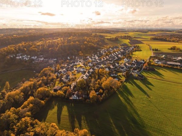 Aerial view of a village surrounded by autumn trees and fields at sunset, Lehenweiler, Aidlingen, Böblingen district, Germany