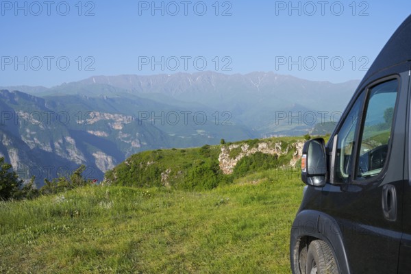 A van stands on a hill with a wide view of a green mountain landscape, camper near Halidzor, Syunik province, Caucasus, Armenia