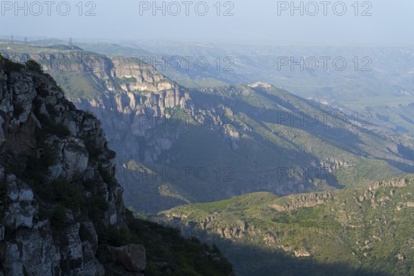Wide view of rocky gorges and green slopes under a blue sky, view of the Vorotan River valley, Vorotan, Halidzor, Syunik province, Caucasus, Armenia