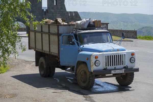 A blue truck transports goods on a rural road with mountains in the background, GAZ-53 loaded with cows, Goris, Syunik province, Syunik, Caucasus, Armenia
