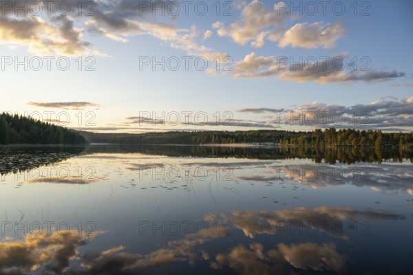 Clouds reflected on the water surface, forest lake, evening mood, at Sunne, Sweden