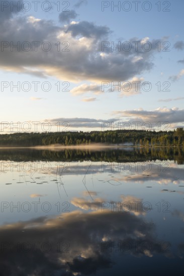 Clouds reflected on the water surface, forest lake, evening mood, at Sunne, Sweden