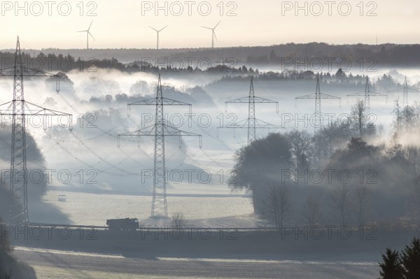 Misty morning landscape with power poles in the foreground and wind turbines, Swabian Jura, Baden-Württemberg, Germany
