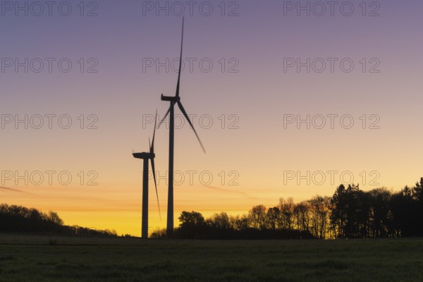 Two wind turbines in front of a devotional sunset. The distinctive silhouettes stand out clearly, Swabian Jura, Baden-Württemberg, Germany
