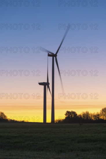 Wind turbines in motion in front of a colorful sunset. The silhouettes of the turbines dominate the scene, Swabian Jura, Baden-Württemberg, Germany