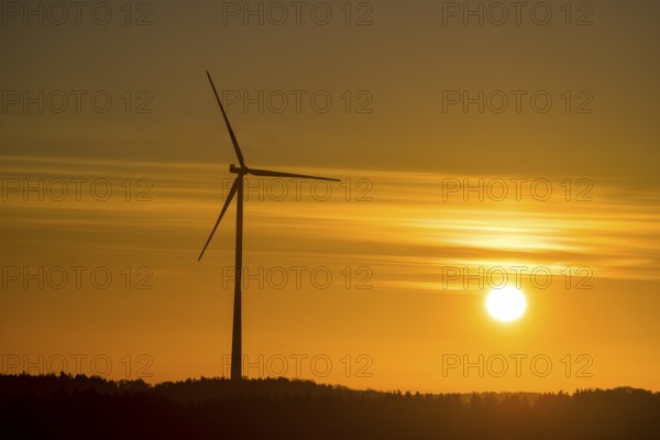 A single wind turbine in front of an intense orange sunset. The sky glows with bright colors, Swabian Jura, Baden-Württemberg, Germany