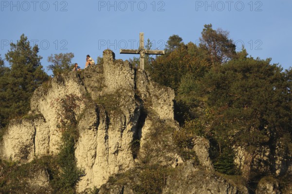 Rocky landscape with summit cross and seated hikers while resting, relaxing, rock formation, rock cliff, landscape, summit, cross, mountain, Pottenstein, Franconian Switzerland, Franconian Jura, Upper Franconia, Bavaria, Germany