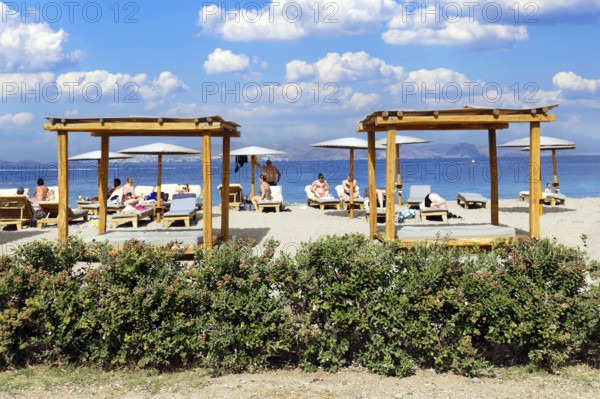 Parasol, sun lounger, sea, pebble beach, piled up with sand, people on the beach, behind Turkish coast, Hotel Mitsis Ramira, Psalidi region, island of Kos, Dodecanese Islands, Greece