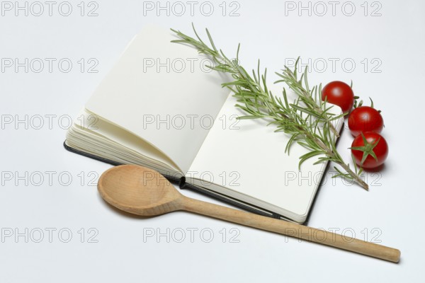 Blank notebook for cooking recipes, cooking spoon with rosemary sprig, tomato