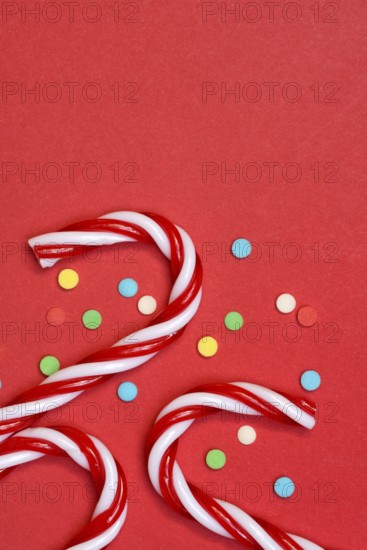 Candy canes and sugar confetti against red background, Christmas