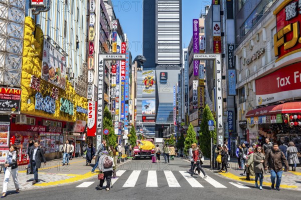 Bustling street scene in Japan with modern buildings and colorful billboards, figure of Godzilla head on a high-rise building, Shinjuku City, Tokyo, Japan