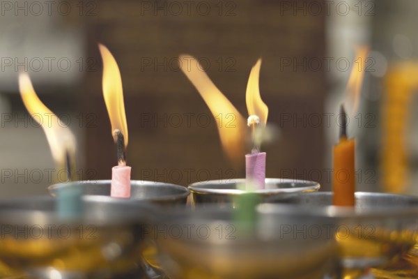 Oil lamps lit by believers as a symbol of the light of wisdom (the light dispels darkness and ignorance) in front of a Buddha statue, Wat Yannawa in the Sathon district, Bangkok, Thailand