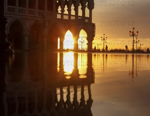 View through the arcades of the Doge's Palace at sunrise on Piazzetta during Acqua Alta, Venice, Veneto, Italy