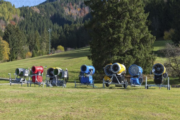 Different snow cannons on an extensive meadow in front of a forest in autumn, Schwangau near Füssen, Ostallgäu, Allgäu, Bavaria, Germany