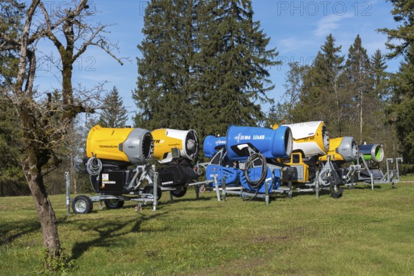 Row of snow cannons in a meadow with trees and partly cloudy sky, Schwangau near Füssen, Ostallgäu, Allgäu, Bavaria, Germany