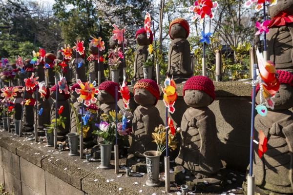 Jizo statues with red crocheted caps, guardian deities for deceased children, Unborn Children Garden, Zojoji temple, Buddhist temple complex, cherry blossom, Tokyo, Japan
