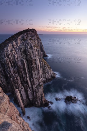 Totem Pole Long exposure at sunrise shows glowing dawn over the dramatic cliffs of Cape Hauy. Waves hit the steep cliffs. Cape Hauy, Tasman Peninsula, Tasmania, Australia