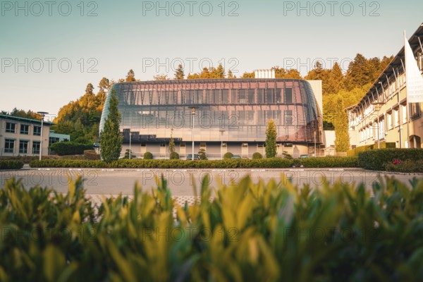 Modern building with glass façade in green surroundings, warm sunlight on the trees, Altensteig, Calw district, Germany