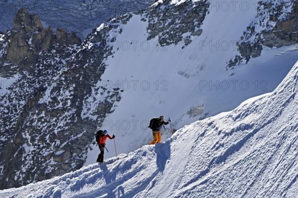 Two mountaineers run across a snow-covered mountain ridge, Aiguille du Midi, Chamonix-Mont-Blanc, Haute-Savoie, France