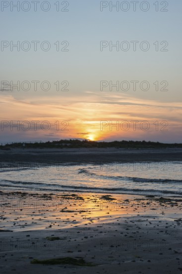 Sunset on a quiet beach with soft light on the waves, wet beach at low tide, dunes in the background, atmospheric, glowing, calm, warm atmosphere, reflecting light on water and beach, reflection, warm and cool tones, orange, yellow, gold, blue, gray, clouds, evening, shade, sandy beach, sand, shore, nobody, maritime, deserted, sea, waves, soft surf, swell, sea, swell, swell, sea, swell, swell, swell, sea, swell, swell, swell, swell, sea, Aade Bay, North Sea, Dune Island, Heligoland, Pinneberg District, Schleswig-Holstein, Germany