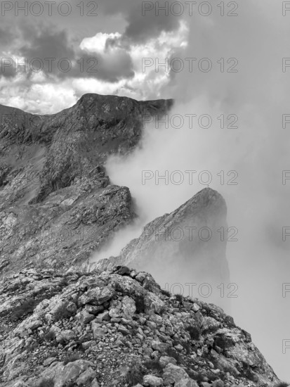 View from the summit of Wildalmkirchl with fog on the southern edge of the Steinernes Meer, monochrome, Berchtesgaden Alps, Austria