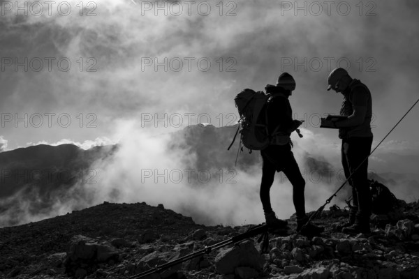 Two mountaineers on the summit of the Brandhorn in the Steinernes Meer, in the background the Hochkönig with the Matrashaus, Berchtesgaden Alps, Austria