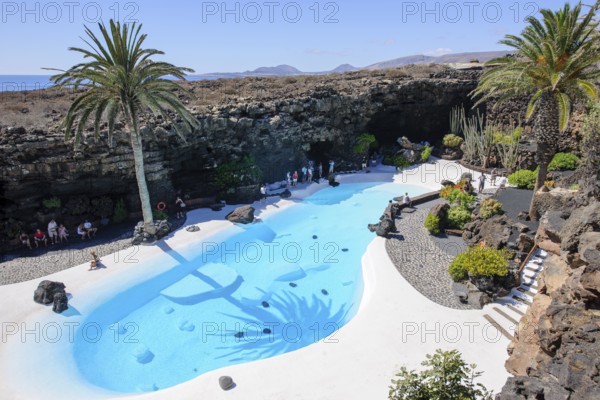 View from elevated position of pool designed by César Manrique Swimming pool in art venue cultural center tourist attraction Jameos del Agua, Punta Mujeres, Lanzarote, in the background East Atlantic, Canary Islands, Spain