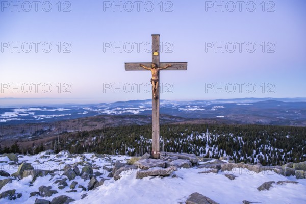 Christian cross on the peak of Mount Lusen with the view over the hills of the bavarian forest at sunrise at winter, Bavaria, Germany