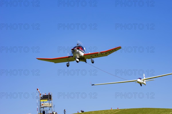 A Robin DR 400/200R Remorqueur light aircraft, registration D-EFGH, tows a glider during a flight demonstration as part of an air show on Rossfeld in Metzingen-Glems, Baden-Württemberg, Germany, for editorial use only