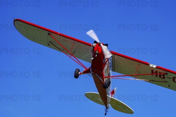 A Piper J-3C/L4 Cub light aircraft, HB-OBF registration, during a flight demonstration as part of an air show on Rossfeld in Metzingen-Glems, Baden-Württemberg, Germany, for editorial use only