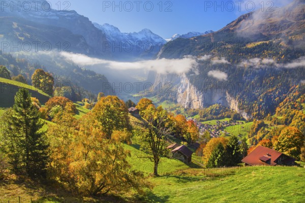 View from the village of the Lauterbrunnen Valley with Staubbach waterfall in autumn with morning fog, Wengen, Bernese Oberland, Canton of Bern, Switzerland
