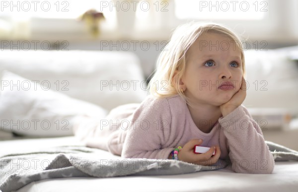 Child, girl, 4 years, blonde, lying on sofa, watching TV, watching television, watching television, excited, Stuttgart, Baden-Württemberg, Germany