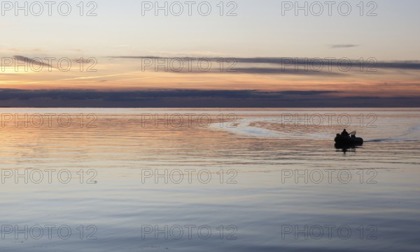 Angler on the beach during sunset, an angler docks on the shore with his inflatable boat and dog, Fehmarn island, 18.10.2025, Fehmarn, Schleswig-Holstein, Germany
