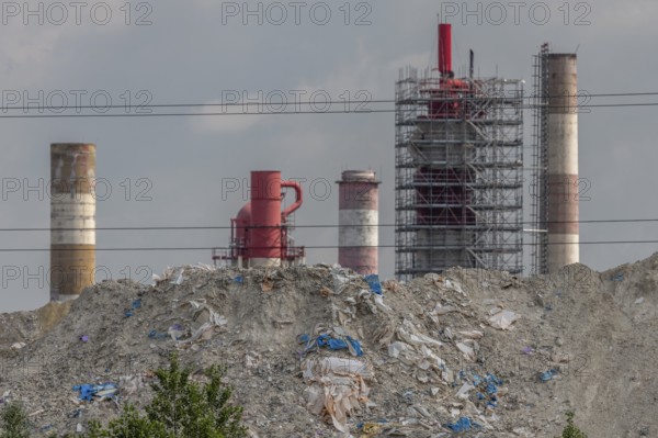 Chimneys, which are not far from factories, rise over mountains of waste. The sky is cloudy and creates a heavily polluted atmosphere. Haut Rhin, Alsace, France