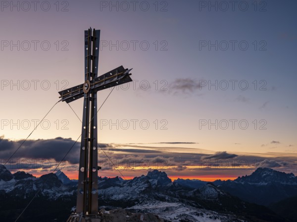 Sassongher summit cross at sunrise, in the background Monte Cristallo, Monte Pelmo and Civatta, Dolomites, Trentino, South Tyrol, Italy